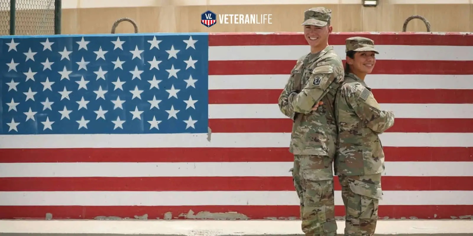 Soldiers standing back to back in front of a flag.