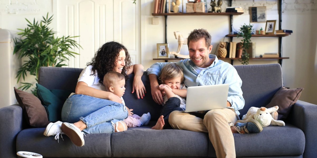 A family sitting together and accessing teletherapy services at home.
