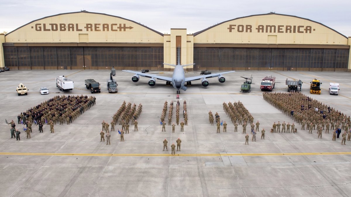 Wide view of troops standing in front of two airplane hangars.