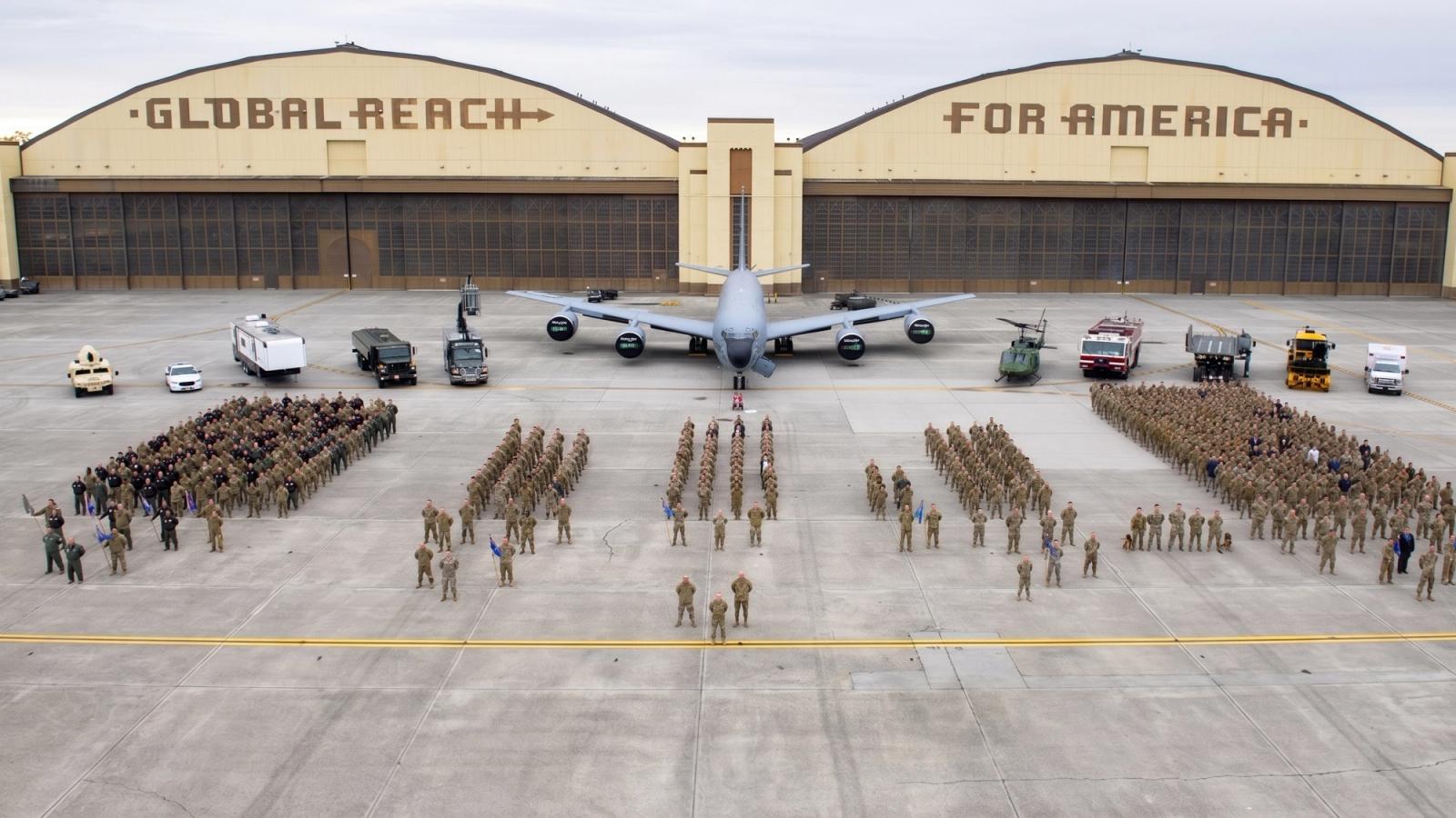 Wide view of troops standing in front of two airplane hangars.