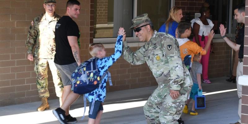 A student attending Pierce Terrace Elementary School at Fort Jackson, S.C., high-fives then-Garrison Command Sgt. Maj. Cesar Duran on the first day of the 2023-24 school year. 