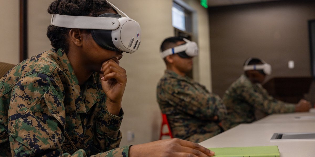 Three soldiers sit in a row wearing virtual reality goggles during training.