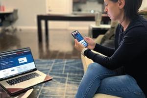 Woman looks at phone and laptop on the VA website.