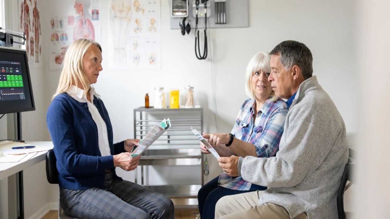 A man and woman speak and point at paperwork in the doctors office.