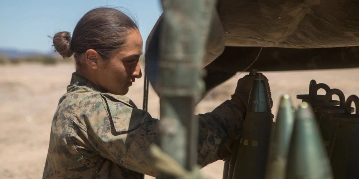 Marine Corps woman loading artillery shells in desert training area