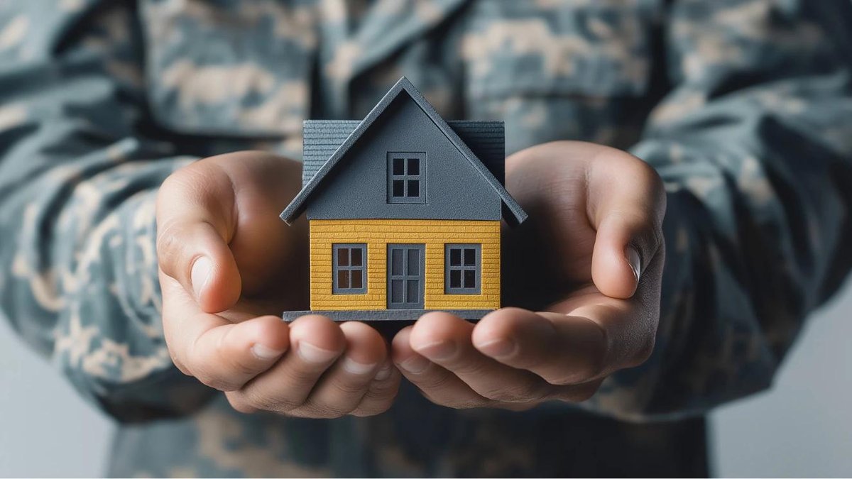 Hands in military uniform holding a small model house, symbolizing VA loan benefits.