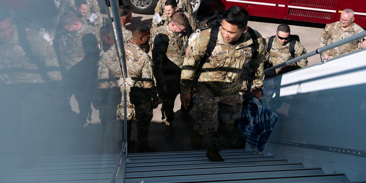 A crowd of soldiers mounts stairs to an aircraft.
