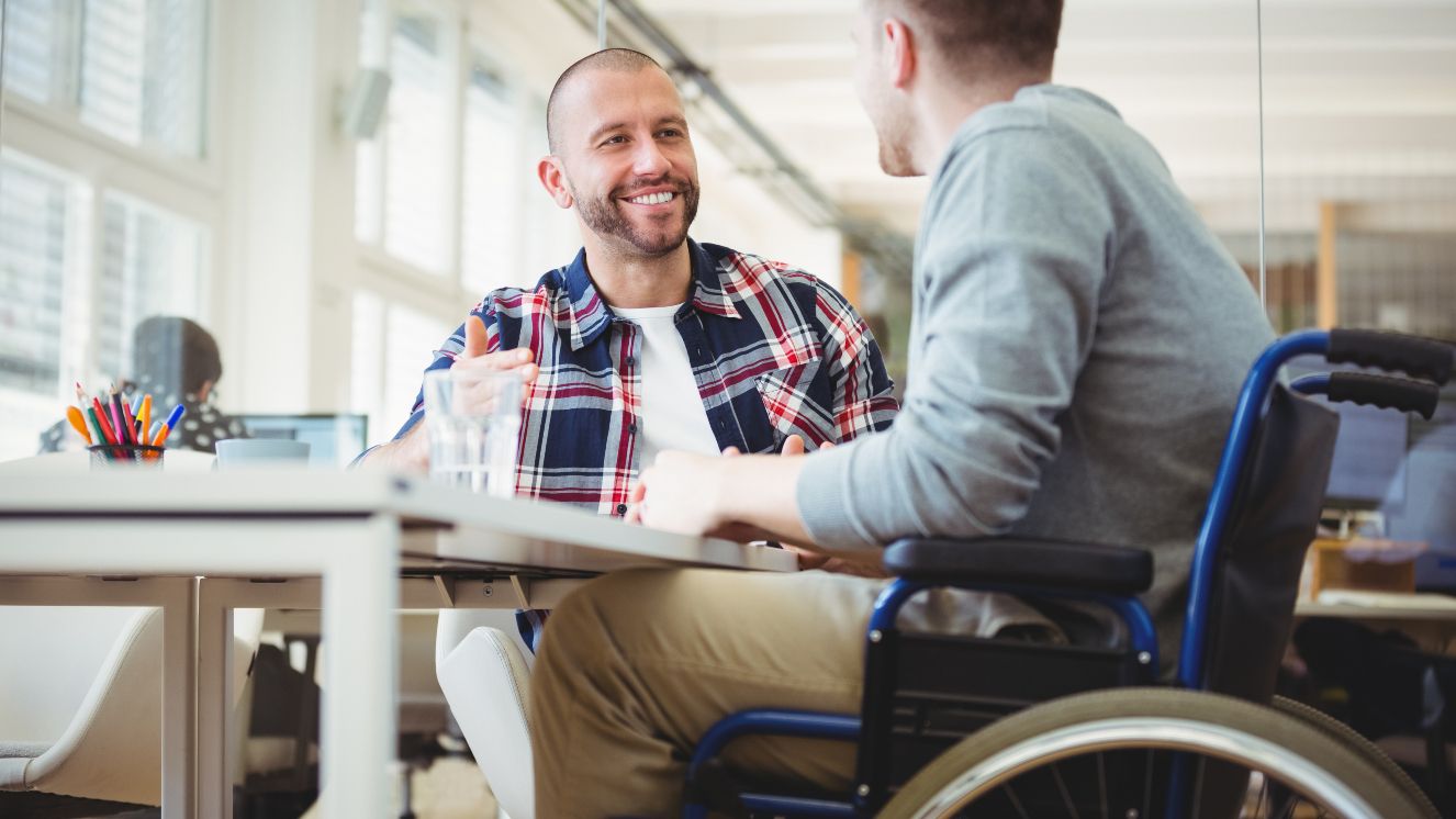 Handicap businessman sitting with colleague in office.