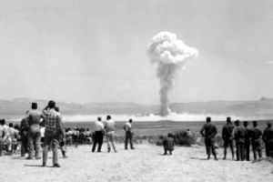 Vintage black-and-white picture of soldiers watching an A-bomb test in Nevada.