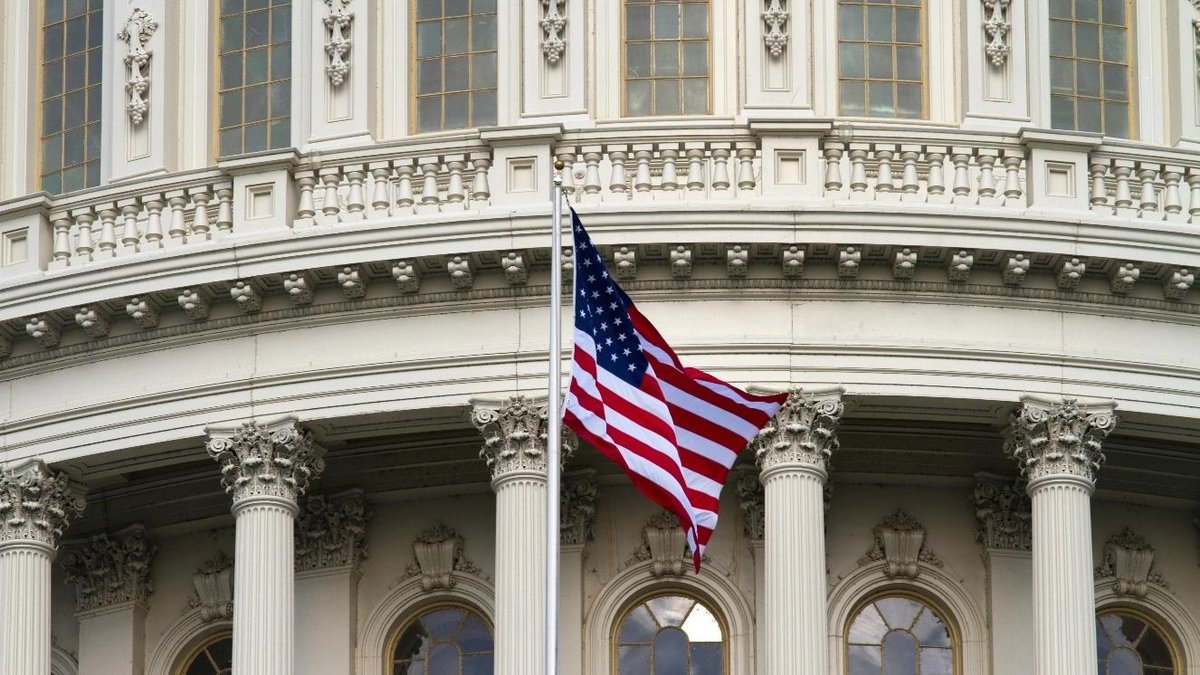 U.S. Capitol building facade with American flag waving in foreground