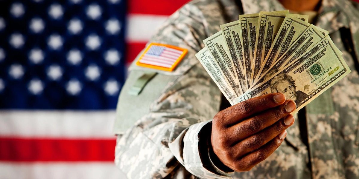 Army soldier holding cash fan with American flag in background