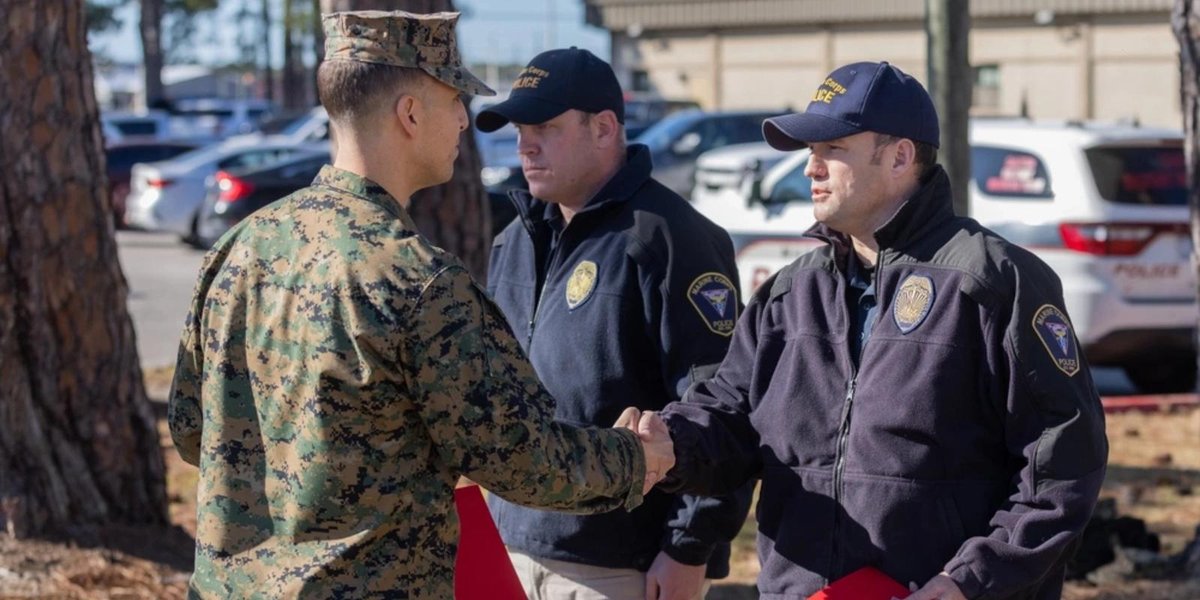 Marine Corps officer shaking hands with police officers in uniform at base parking lot