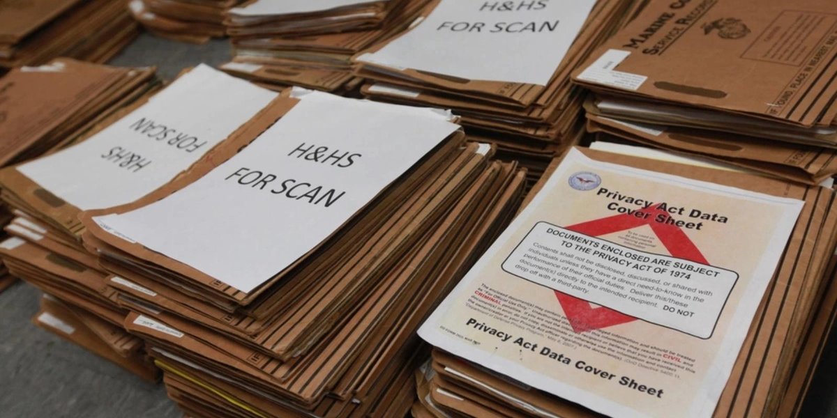 Stacks of military service record files with Privacy Act Data cover sheets.