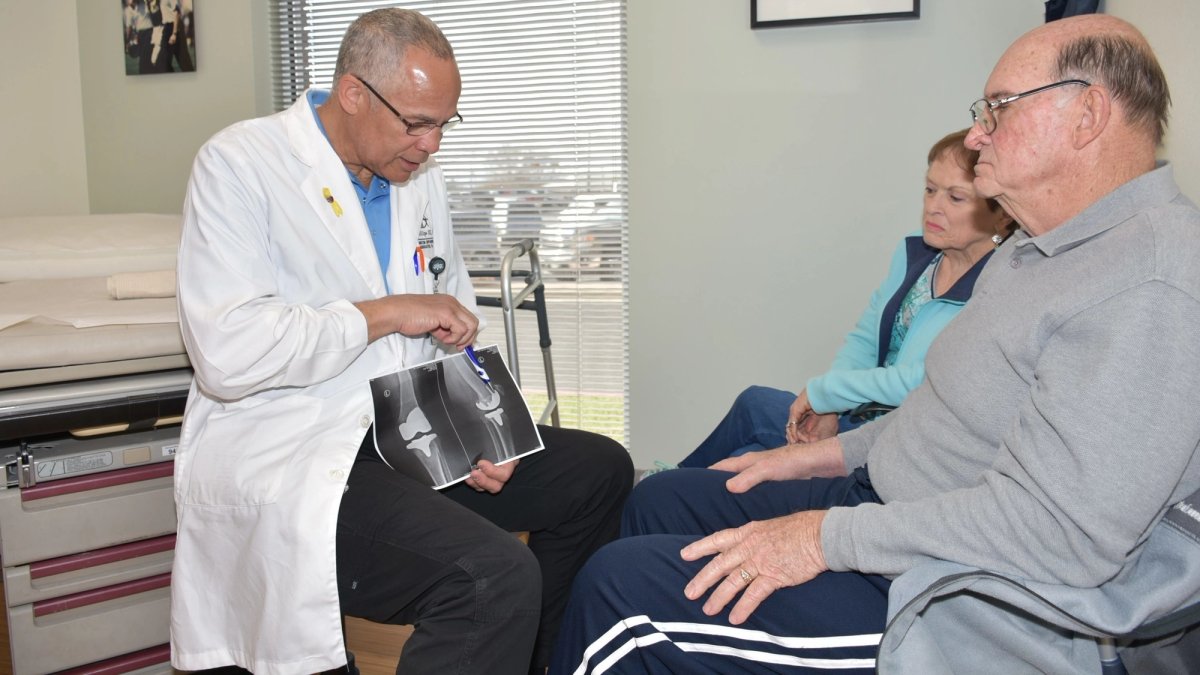 A doctor explaining an X-ray to a patient and his wife.