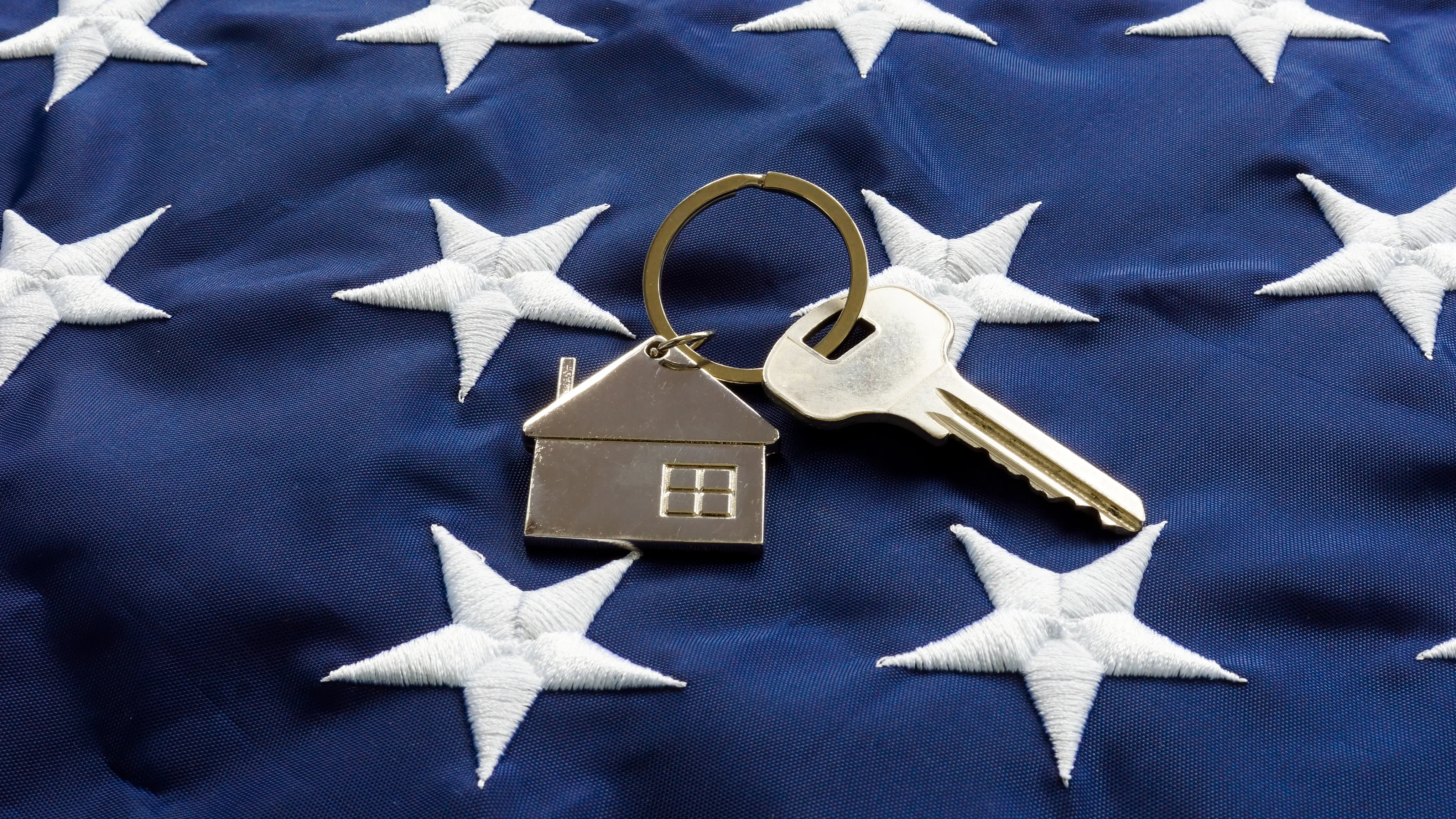 Still life of House-shaped key fob and key on a flag.