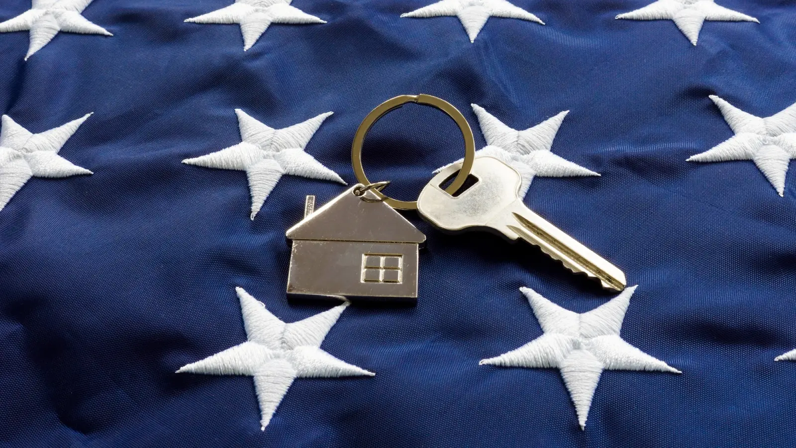 Still life of House-shaped key fob and key on a flag.