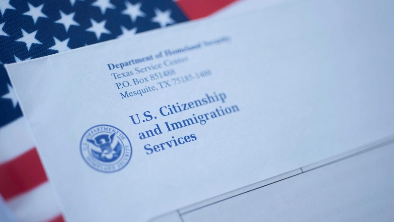 Blurred Letter (Envelope) from USCIS on flag of USA background.