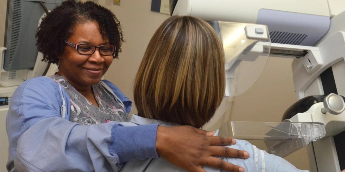 Medical professional assisting woman with mammogram machine