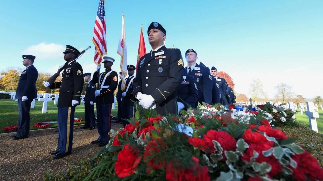 Military honor guard at cemetery with flags during Veterans Day ceremony