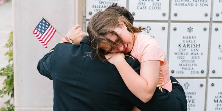 A man embraces a sad girl in front of a memorial.