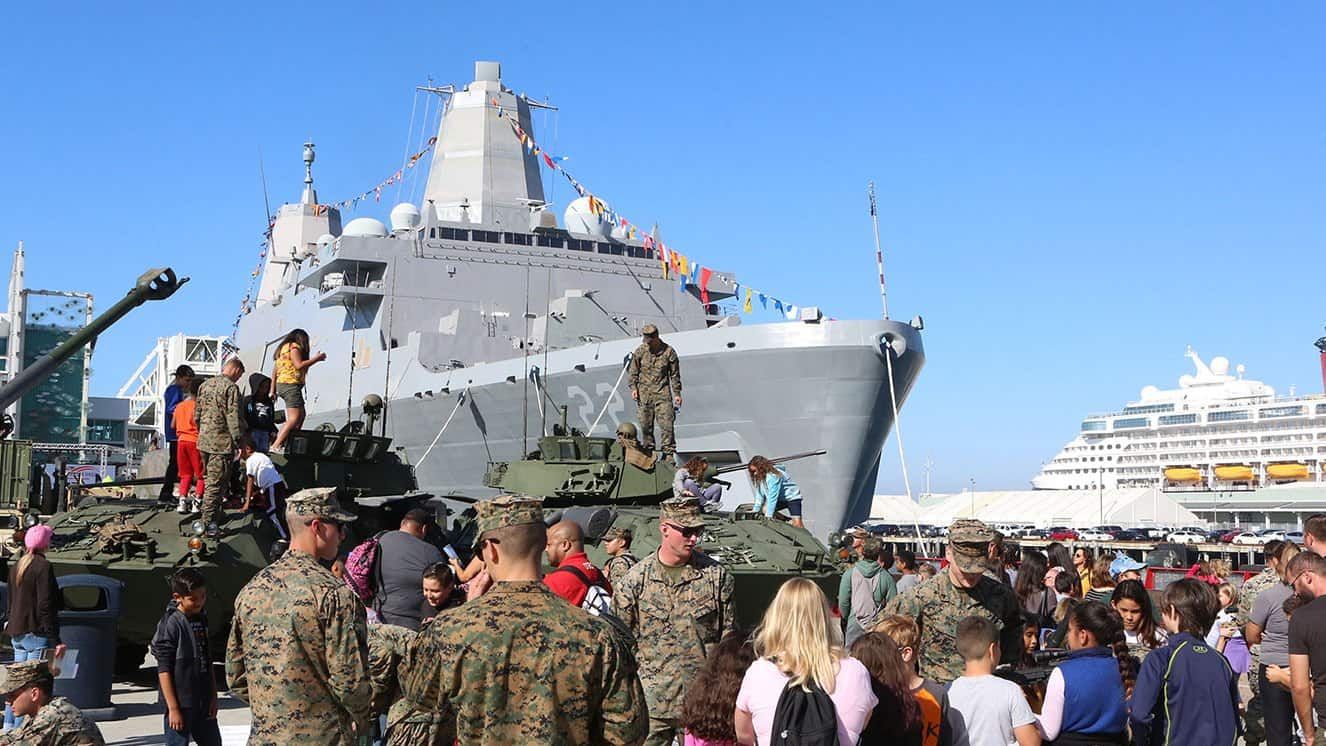 Crowds explore Marine Corps vehicles near Navy ship during Fleet Week San Diego.