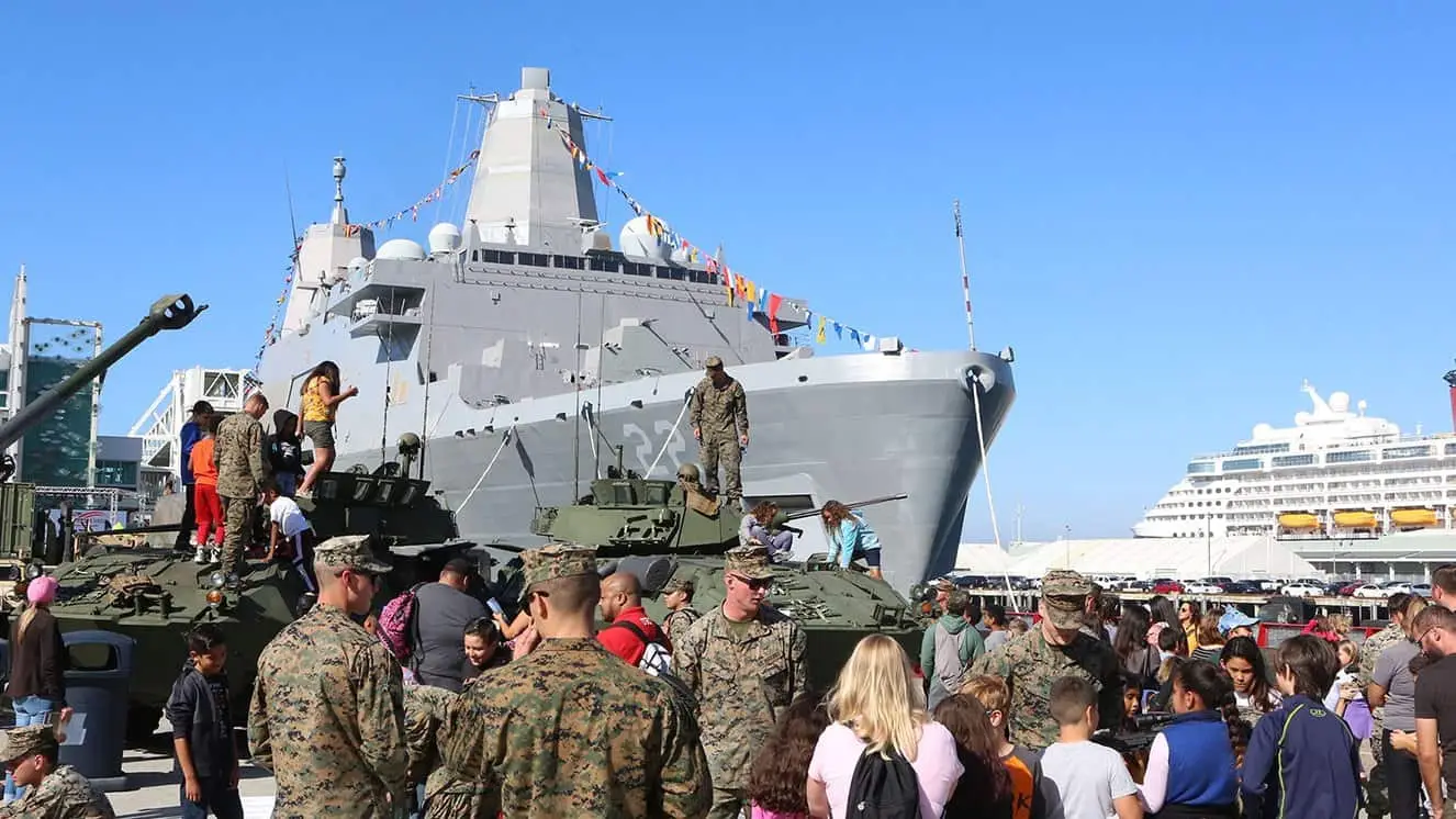 Crowds explore Marine Corps vehicles near Navy ship during Fleet Week San Diego.