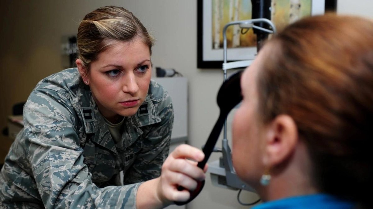 Air Force optometrist conducting an eye exam on a female veteran in a clinic setting