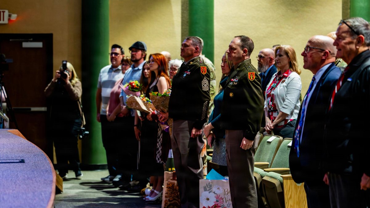 Servicemen and families stand at a retirement ceremony.