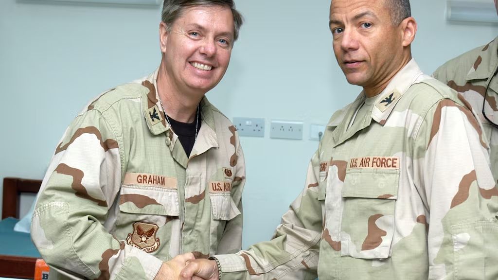 A uniformed Lindsey Graham shakes the hand of another airman.