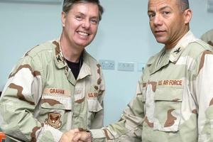 A uniformed Lindsey Graham shakes the hand of another airman.