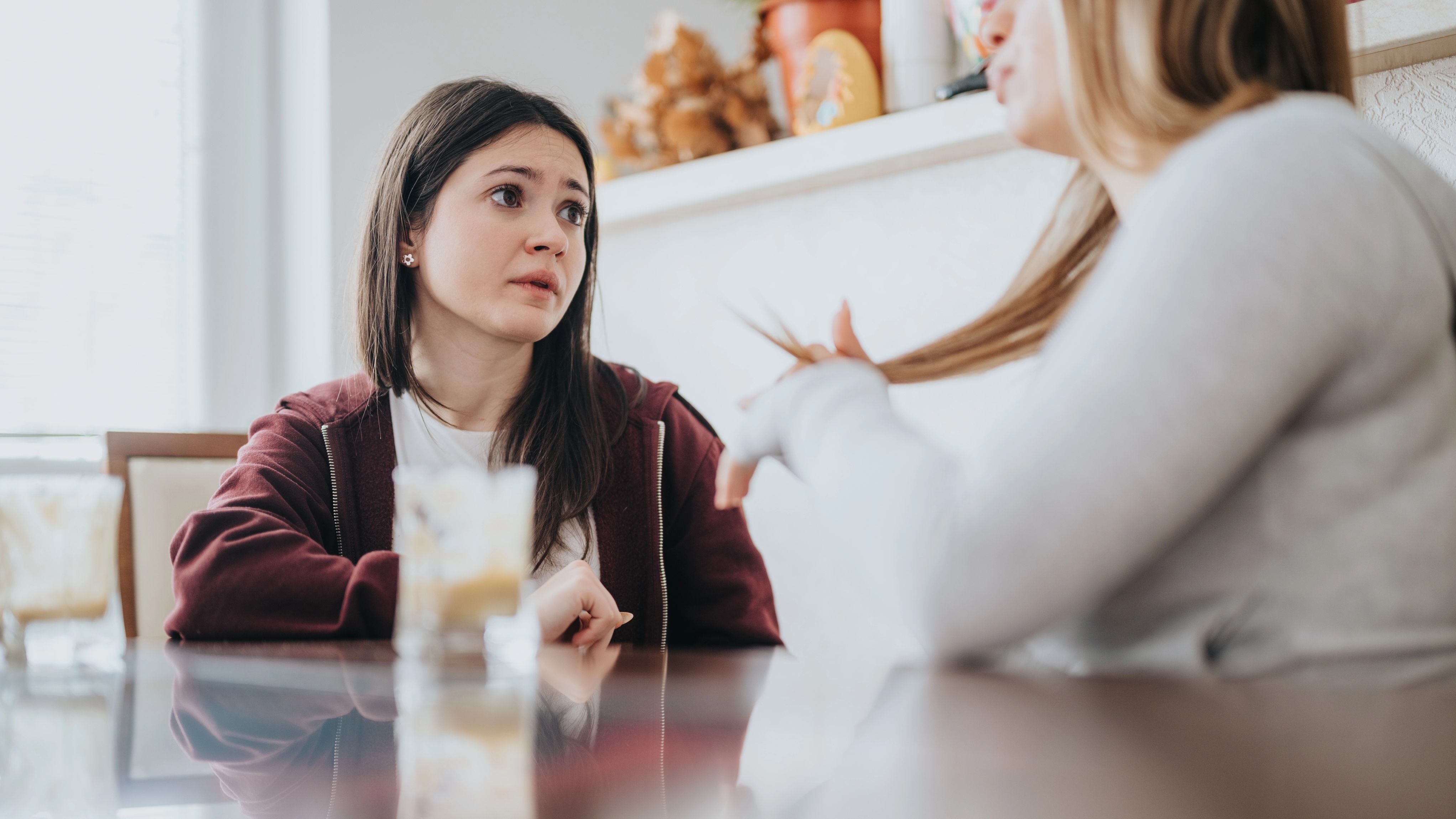 Two women sit and talk at a table.