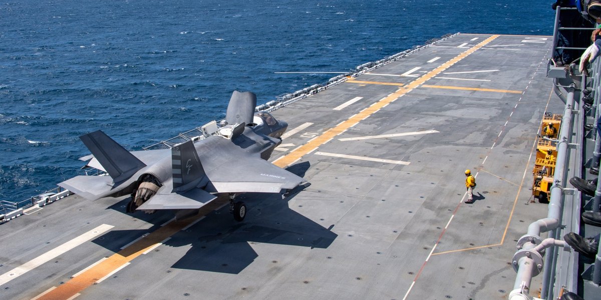 A fighter jet landing on a ship in the ocean.