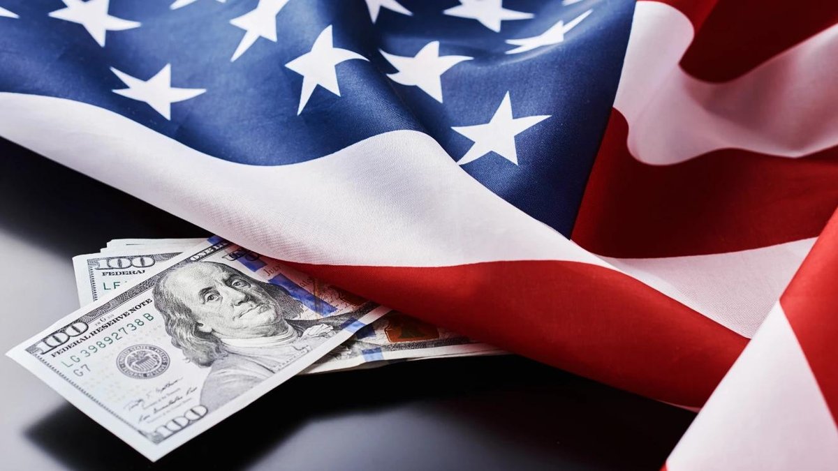 American flag draped over US hundred-dollar bills