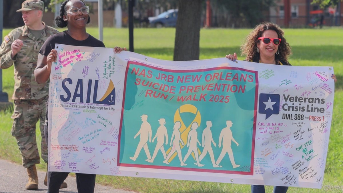 U.S. Army Spc. Mariya A. Washington, left, an information technology specialist, and Marcela Moody, Suicide Prevention Program manager assigned to the 377th Theater Sustainment Command, carry a banner during the Suicide Prevention Run/Walk at Naval Air Station Joint Reserve Base.