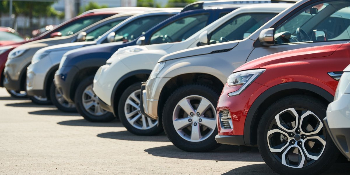A row of different colored cars in a parking lot.