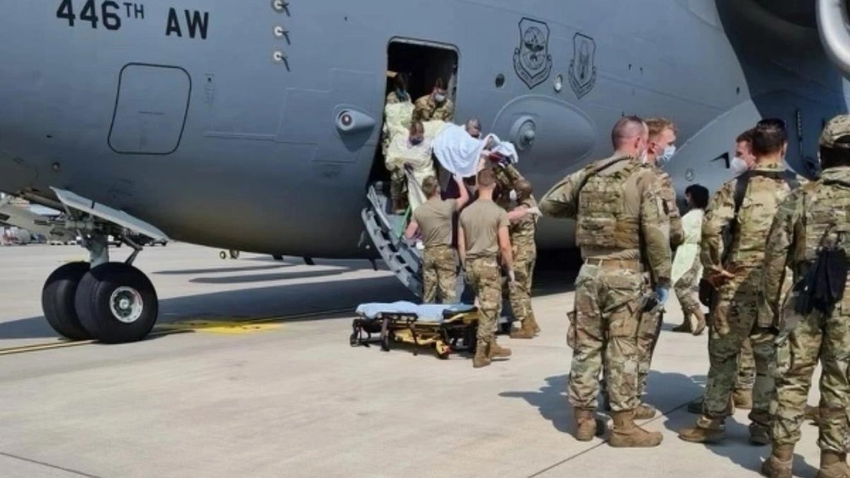 Soldiers assisting evacuees boarding USAF C-17 at airbase.