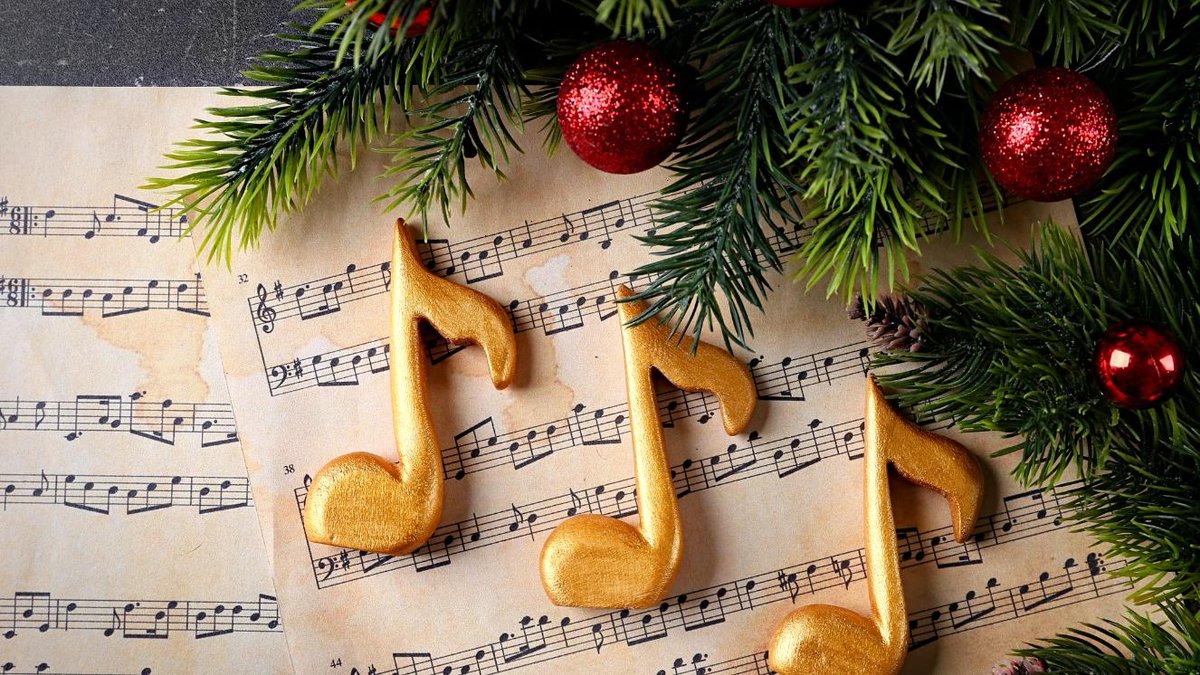 Sheet music with festive decorations of pine branches and red ornaments.