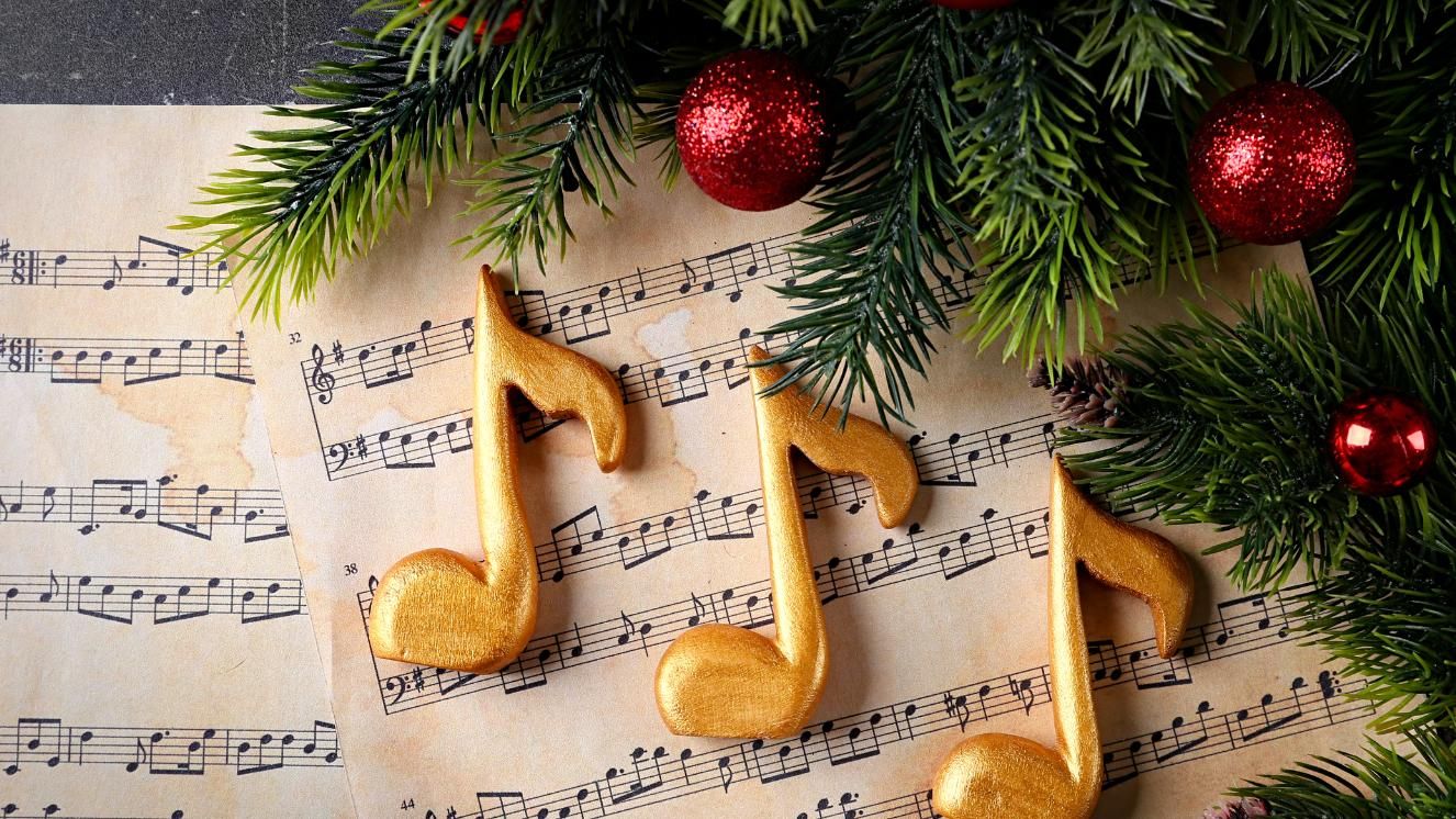 Sheet music with festive decorations of pine branches and red ornaments.