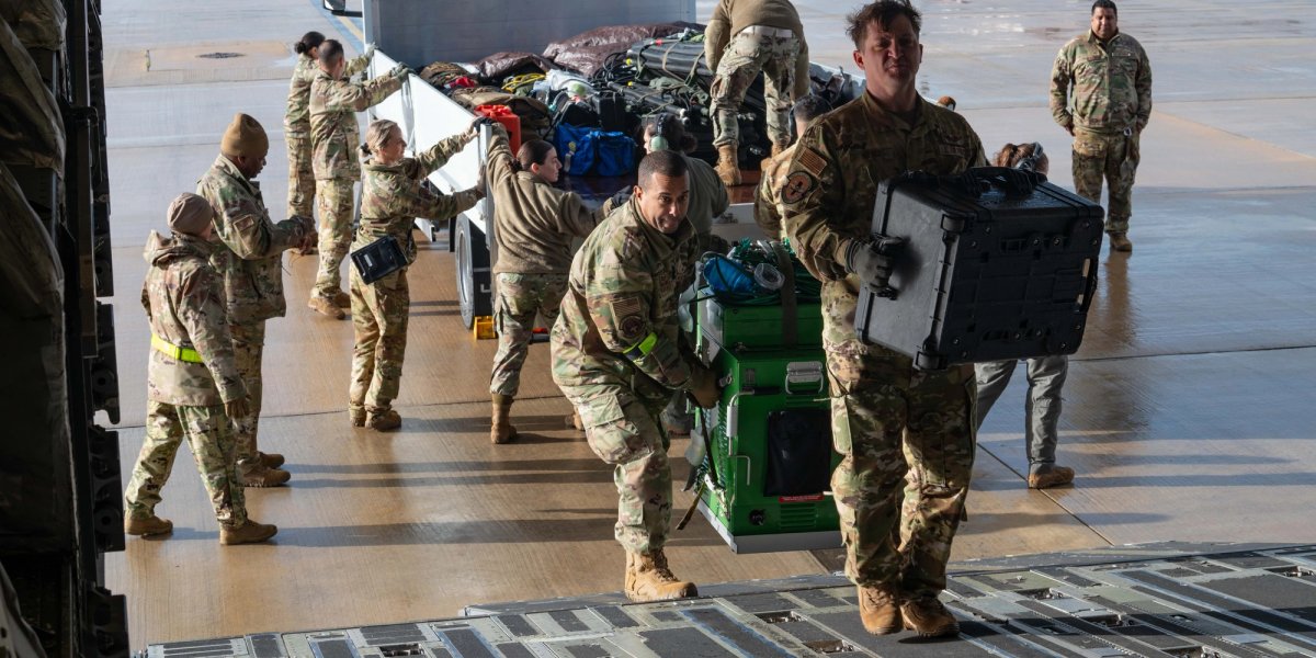 A group of uniformed men walk up a ramp to load a tanker plane.