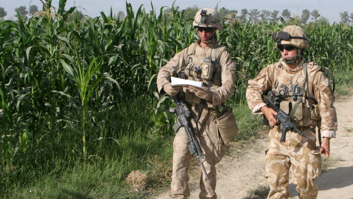 Two Marines in battle uniform walk through a danger zone.