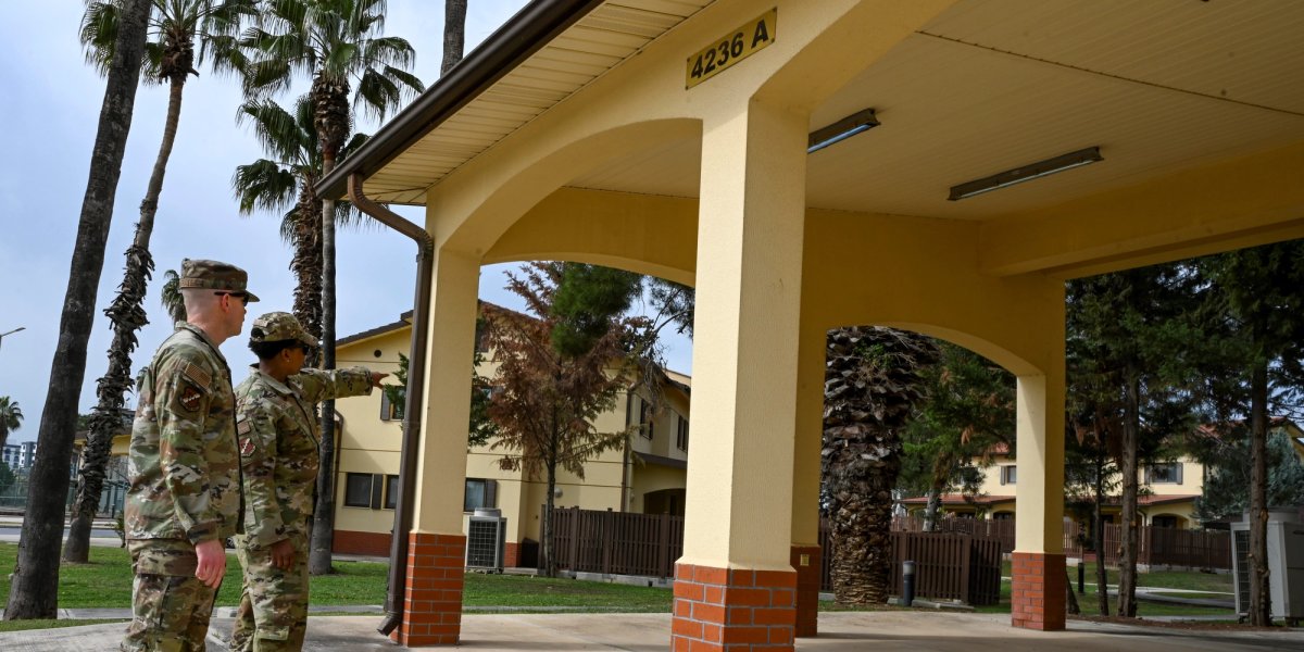 Two soldiers stand outside of OCONUS military housing.