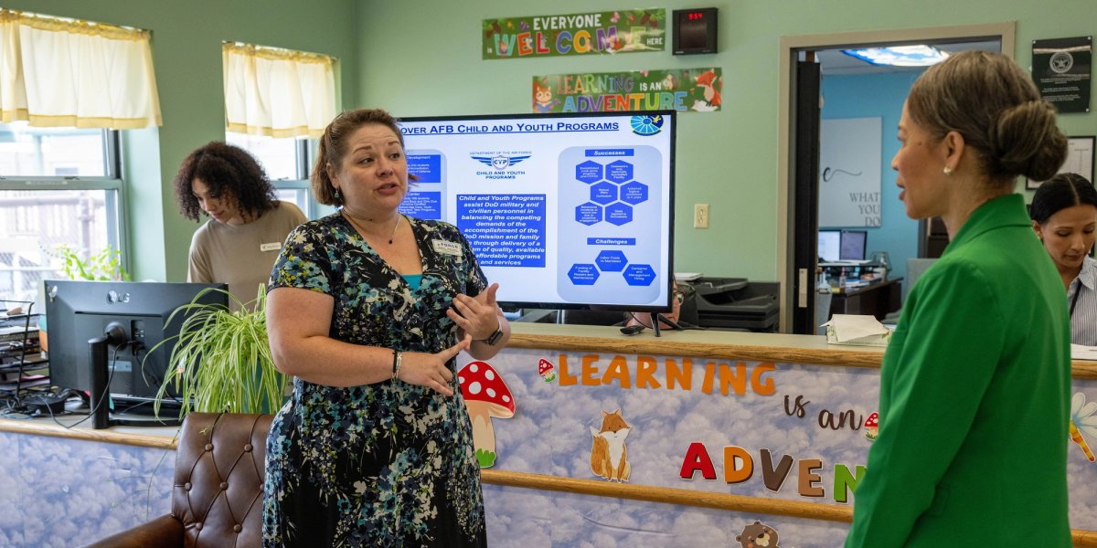 Two professional women speak in an office setting.