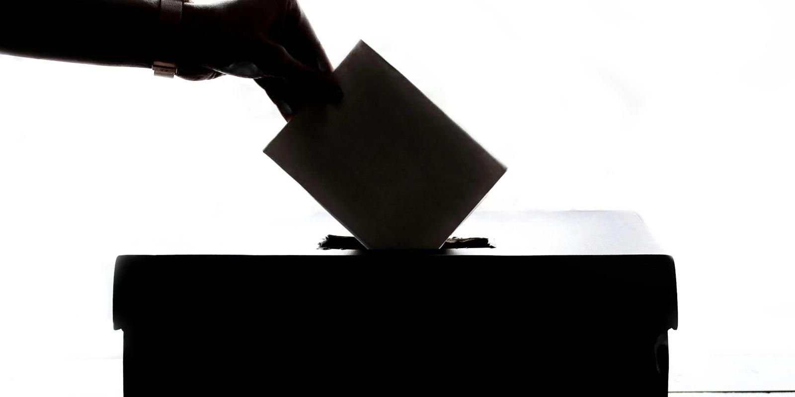 Ballot being cast into a voting box, highlighting military absentee voting process