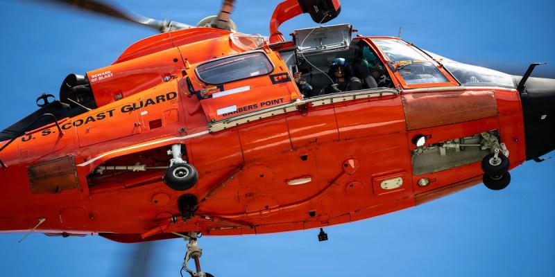 U.S. Coast Guard Petty Officer 1st Class Matthew Miller, an aviation maintenance technician assigned to Coast Guard Air Station Barbers Point in Kapolei, Hawaii, looks down from a Barbers Point MH-65 Dolphin helicopter during training at Bellows Air Force Base in Waimanalo, Hawaii, April 29, 2026.