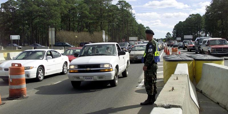 A US Army (USA) Military Police checks the identification of motorists entering the Main Gate at Fort Stewart, Georgia.