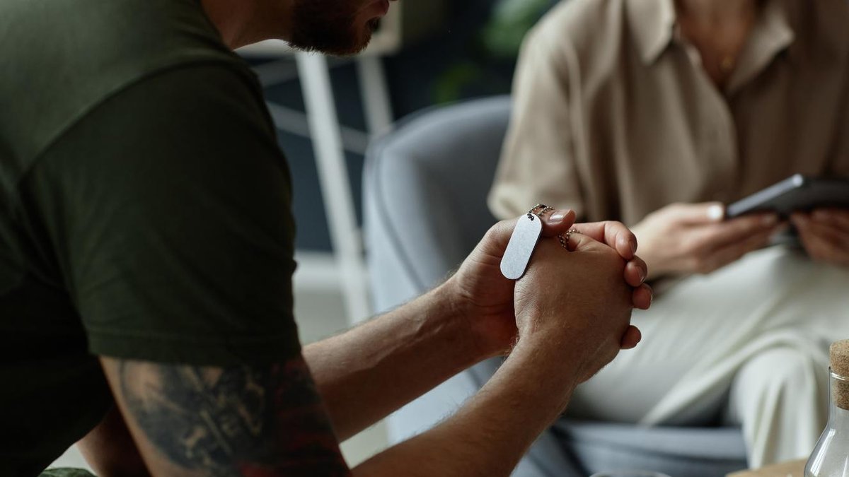 Veteran holding dog tags during a support session in a counseling room