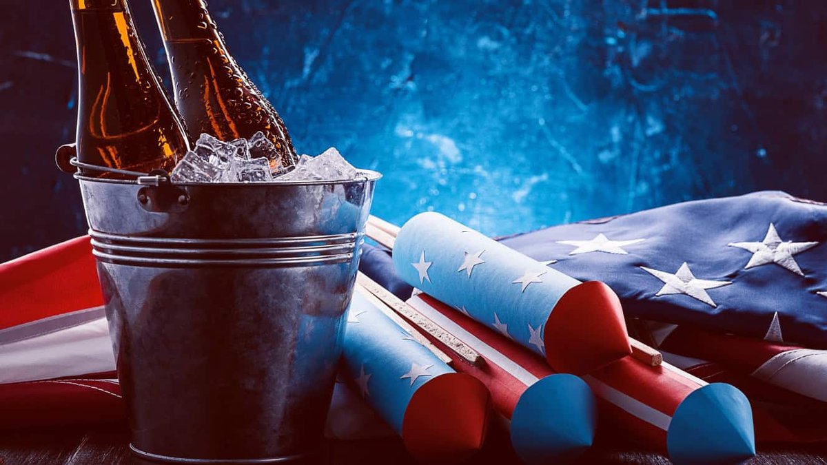 American flag and fireworks next to a bucket of iced beer bottles.