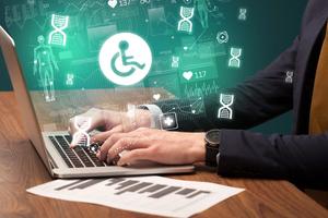 Close-up of a man's hands typing on a laptop, with digital type and disability symbols floating around as an illustration.