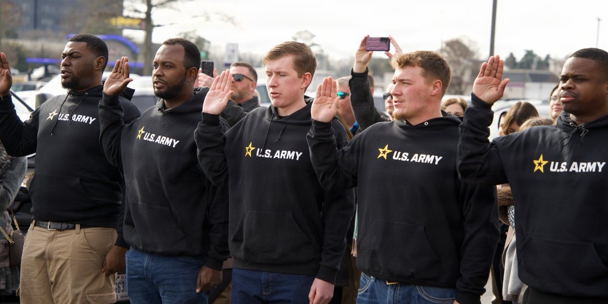 Rows of new recruits take the oath as they raise their right hands.