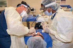 A dentist and assistant work on a patient.